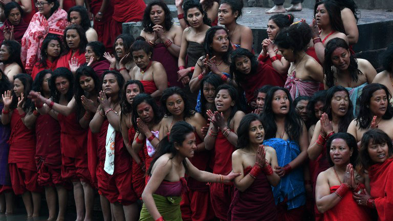 Devotas oferecem orações antes de tomarem banho sagrado no rio Bagmati durante festival em Katmandu (Crédito: PRAKASH MATHEMA / AFP) Devotas oferecem orações antes de tomarem banho sagrado no rio Bagmati durante festival em Katmandu (Crédito: PRAKASH MATHEMA / AFP)